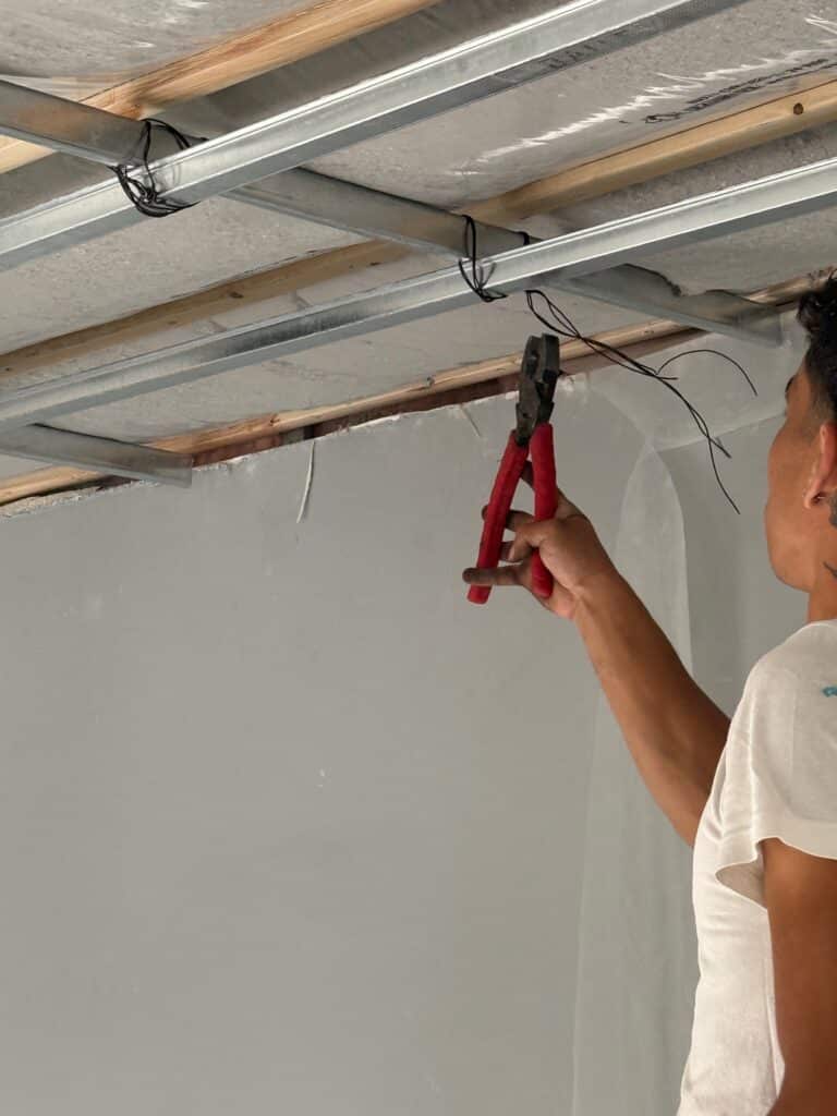 Basement ceiling assembly with limited structural contact and dense-packed cellulose installation.