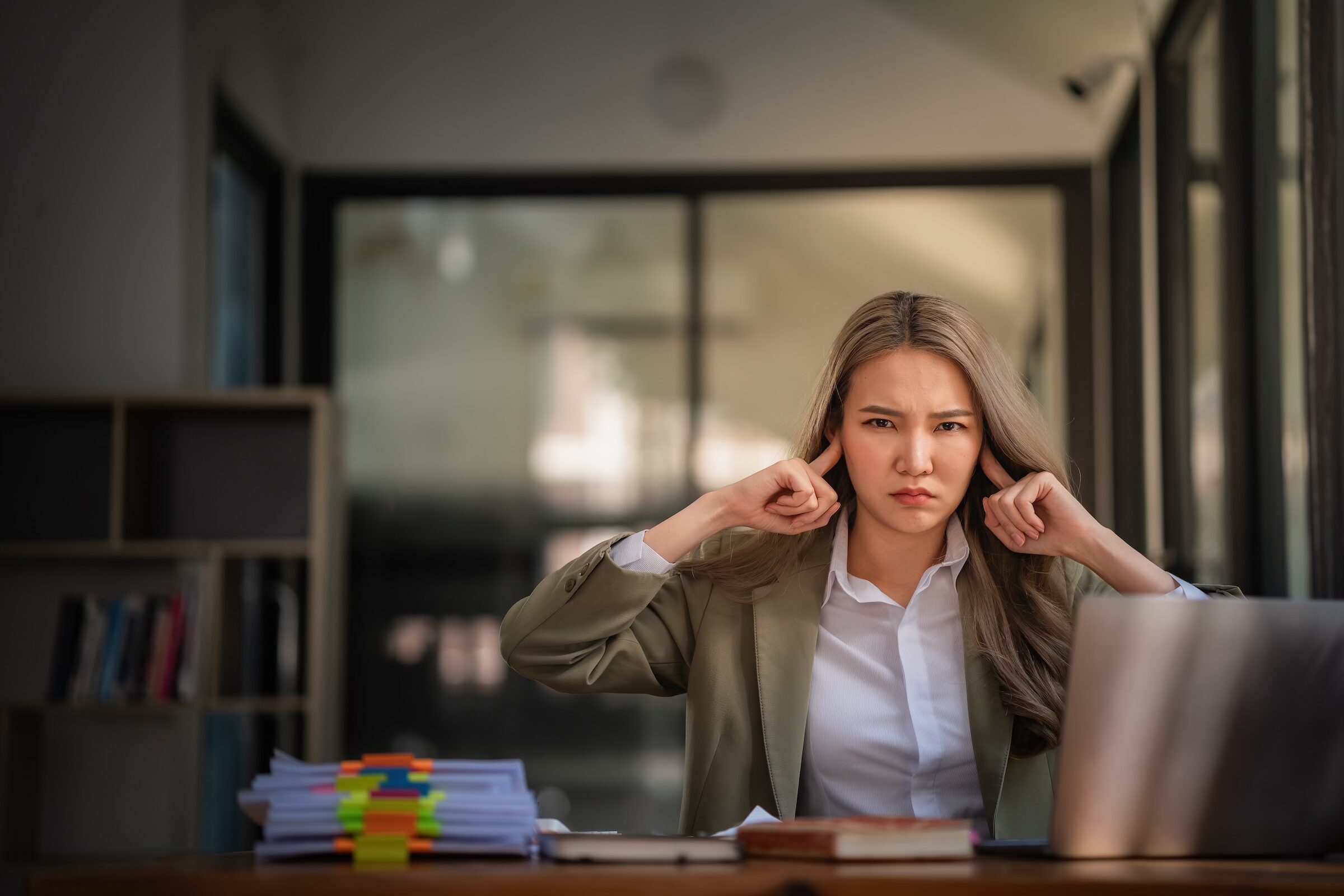 Woman frustrated by noise at work, seeking soundproofing solutions.